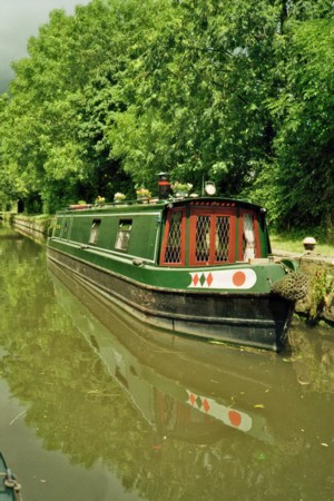 A green and red painted narrow boat on the local canal